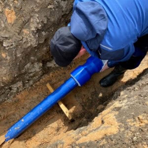 Image-(6) Ein Bauarbeiter steckt die Steckverbindungen Reinogrip in einem Graben auf ein Trinkwasserrohr